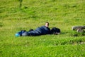 Young woman summerÃÂ hiker with backpack lying in her sleeping bag on meadow after hike. Female trekker relaxing on grass in Royalty Free Stock Photo